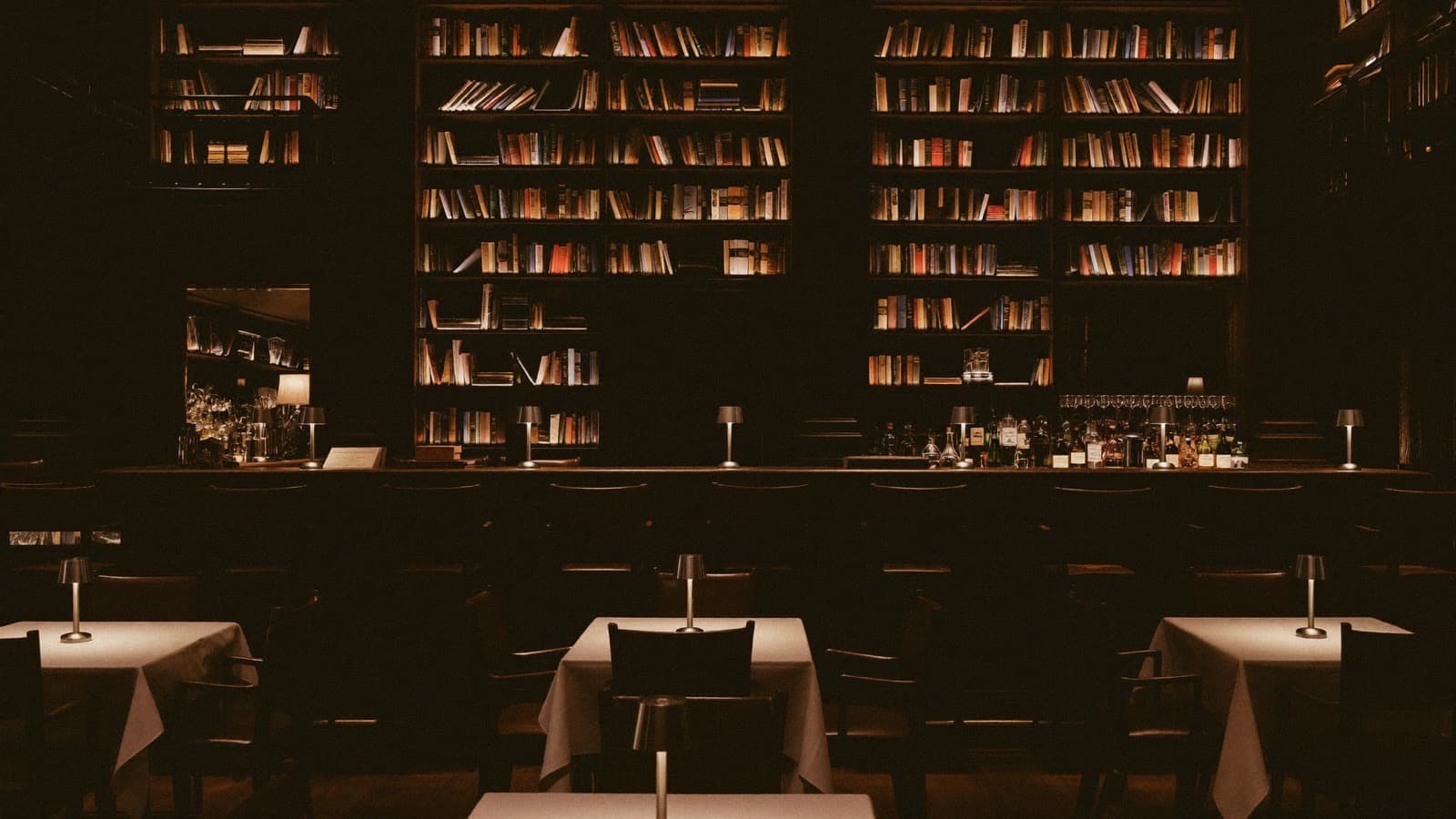 Boceto del restaurante del club: biblioteca, mesas con mantel blanco y luz cálida