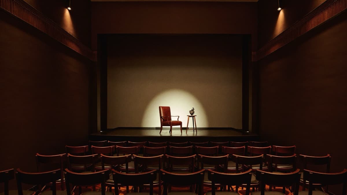 Salón de actos íntimo con escenario bajo un foco cálido